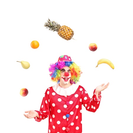 A smiling clown juggling fruits isolated against white backgroundの写真素材