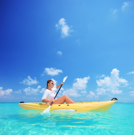 A young female in a yellow kayak kayaking near a Kuredu island, Maldives, Lhaviyani atollの写真素材