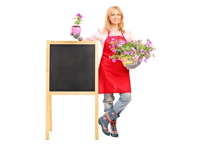 Full length portrait of a female florist holding flowers and posing next to a board isolated on white backgroundの写真素材