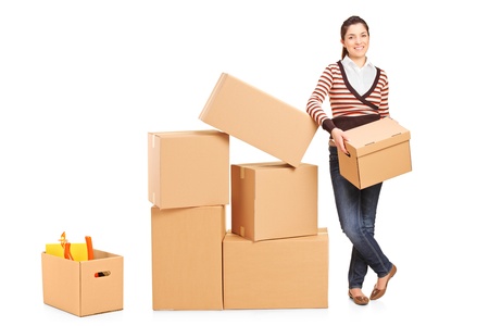 Smiling woman holding a box and many other boxes around her isolated on white backgroundの写真素材