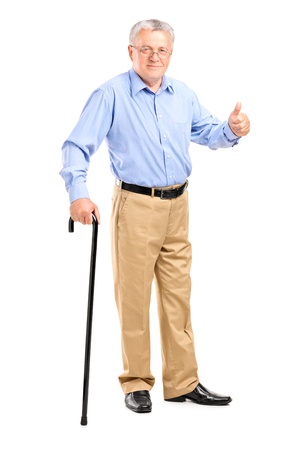 Full length portrait of a senior man holding a cane and giving thumb up isolated on white backgroundの写真素材