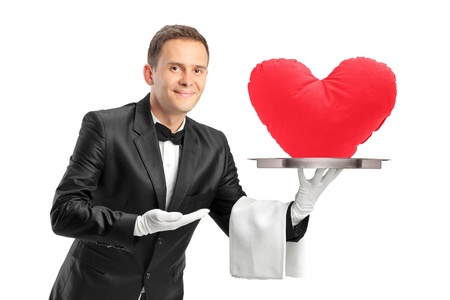 A butler holding a tray with a red heart shape object on it isolated on white backgroundの写真素材