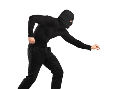 A man in robbery mask trying to steal something isolated on white backgroundの写真素材