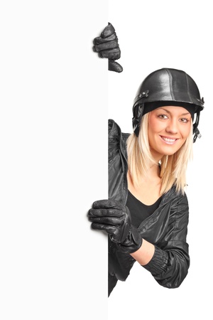 A portrait of a smiling female motorcyclist holding a blank panel isolated on white backgroundの写真素材