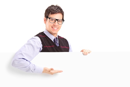 A smiling handsome guy gesturing on a white panel isolated on white backgroundの写真素材
