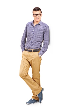 Full length portrait of a young male leaning against wall isolated on white backgroundの写真素材