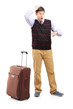 Full length portrait of a shocked man looking at his watch and his luggage, isolated on white backgroundの写真素材