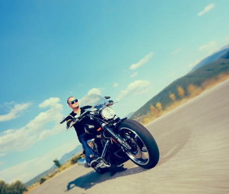 Biker riding a customized motorcycle on an open road shot with a tilt and shift lens and with very shallow depth of fieldの写真素材