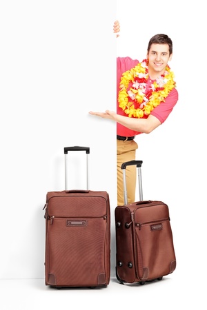 Young man with suitcases posing behind panel isolated on white backgroundの写真素材