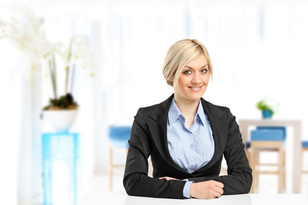 A blond smiling businesswoman sitting at her deskの写真素材