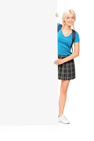 Full length portrait of a female student posing behind a blank panel isolated on white backgroundの写真素材
