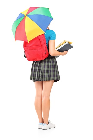 Full length portrait of a female student holding an umbrella, isolated on white backgroundの写真素材