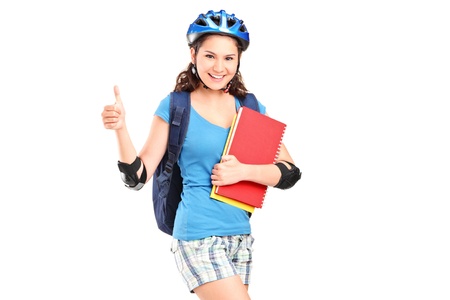 A girl on rollers holding notebooks and giving thumb up isolated against white backgroundの写真素材