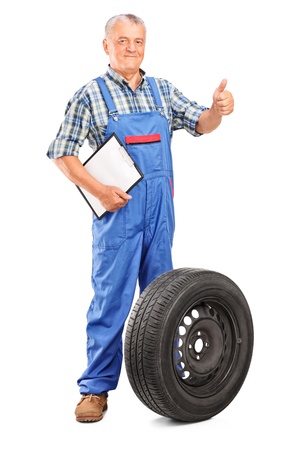 Full length portrait of a mature mechanic with tyre isolated on white backgroundの写真素材