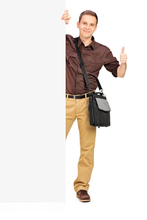 Full length portrait of a young man posing with white panel and giving a thumb up isolated on whiteの写真素材
