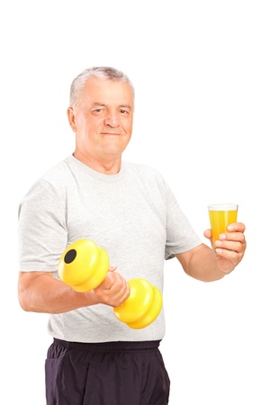 Mature man holding a dumbbell and glass of juice isolated on white backgroundの写真素材