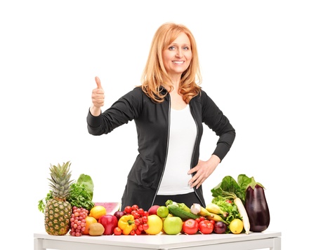 Woman with fruits and vegetables giving a thumb up isolated on white backgroundの写真素材