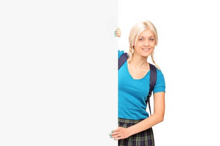 A female student posing behind a blank panel isolated on white backgroundの写真素材