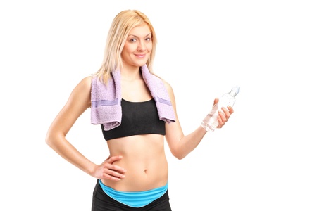 An attractive sportswoman with a bottle of water posing after training isolated on whiteの写真素材