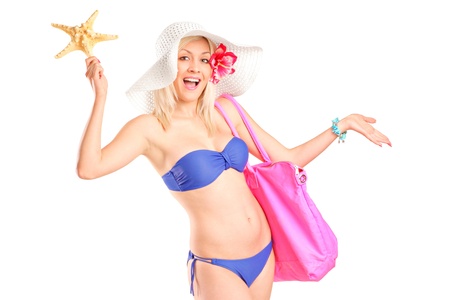 Beautiful young woman in bikini holding a starfish and bag, isolated on white backgroundの写真素材