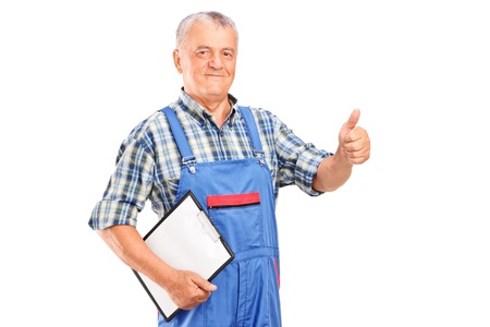 Mature mechanic holding a clipboard and giving a thumb up isolated on white backgroundの写真素材