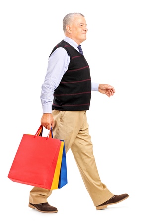 Full length portrait of a mature man coming back after shopping isolated on white backgroundの写真素材