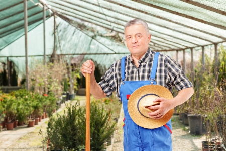 Male worker holding a shovel and posing in a flower gardenの写真素材