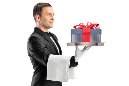 A butler with bow tie carrying a tray with gift on it isolated against white backgroundの写真素材