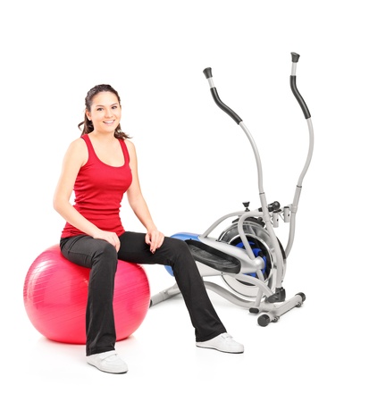 Young female resting on a pilates ball next to a cross trainerの写真素材