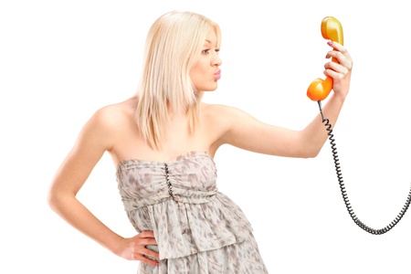A female holding a telephone and giving kisses isolated on white backgroundの写真素材