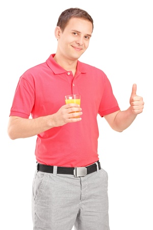 Casual guy holding a glass of orange juice and giving thumb up isolated on white backgroundの写真素材