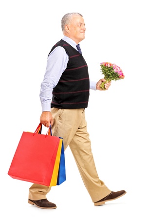 Full length portrait of a gentleman carrying gifts and bouquet isolated on white backgroundの写真素材