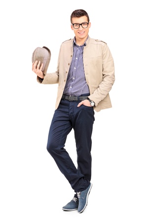 Full length portrait of a young man holding a hat isolated on whiteの写真素材