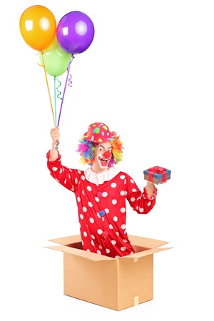 Clown holding balloons and a gift in a cardboard box, isolated on white backgroundの写真素材