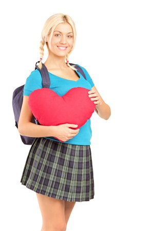 A blond beautiful student holding a heart shape object isolated on white backgroundの写真素材