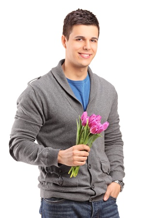Smiling handsome male holding tulips against white backgroundの写真素材