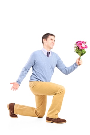 A smiling male kneeling and holding a bouquet of flowers isolated on white backgroundの写真素材