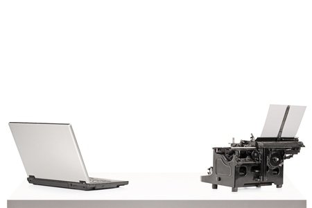 A laptop and old style typing machine on a table isolated on white background