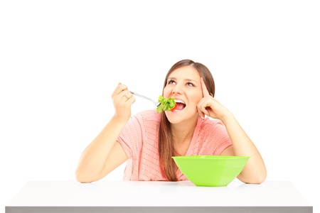 A smiling female eating salad isolated against white backgroundの写真素材