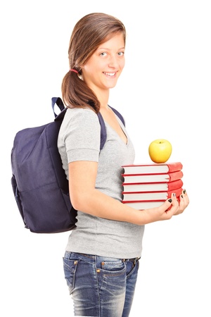 A smiling schoolgirl holding books and green apple isolated on white backgroundの写真素材