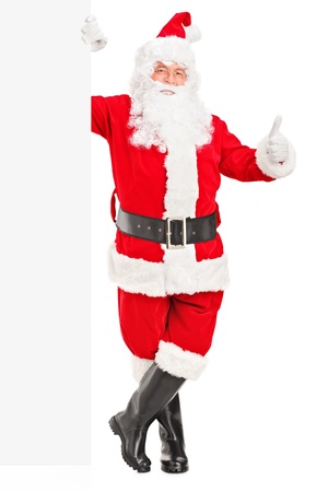 Full length portrait of a happy Santa claus standing next to a blank billboard and giving a thumb up の写真素材
