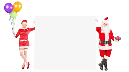 Full length portrait of a male and female Santa Clauses holding a blank panel isolated on white backgroundの写真素材