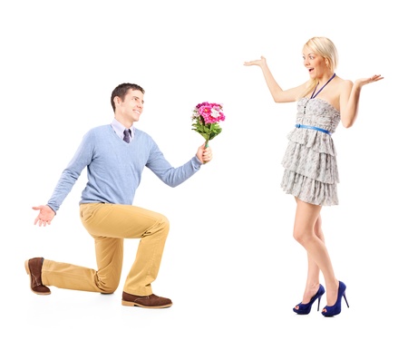 A male kneeling with a bunch of flowers and excited female isolated on white backgroundの写真素材