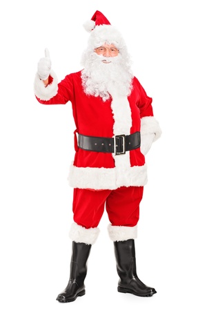Full length portrait of a happy Santa claus standing and giving a thumb up isolated on white backgroundの写真素材