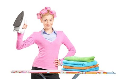 A smiling woman with hair rollers holding an iron and ironing board isolated on white backgroundの写真素材