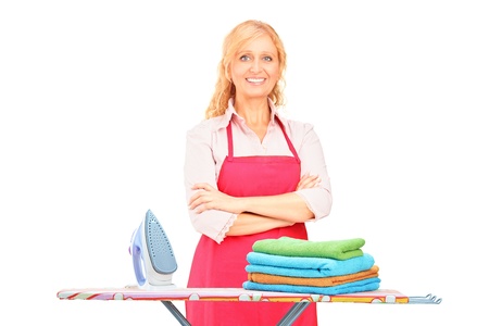 Woman standing next to an ironing board isolated on white backgroundの写真素材