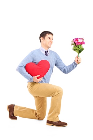 Smiling male kneeling with bouquet of flowers and red  heart isolated on white backgroundの写真素材