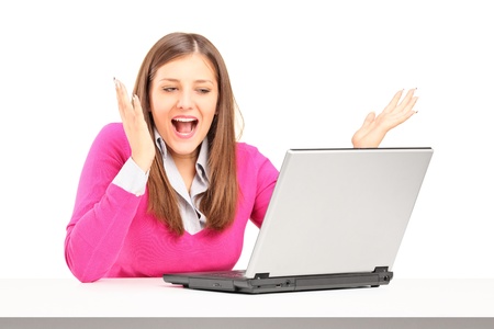 Excited young female working on laptop isolated on white backgroundの写真素材