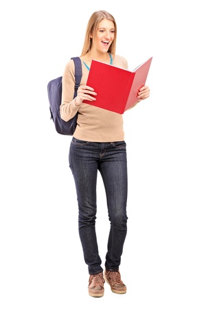 Full length portrait of a female student reading a book isolated against white backgroundの写真素材