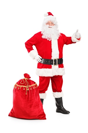 Full length portrait of a happy Santa Claus with a bag giving a thumb up isolated on white backgroundの写真素材